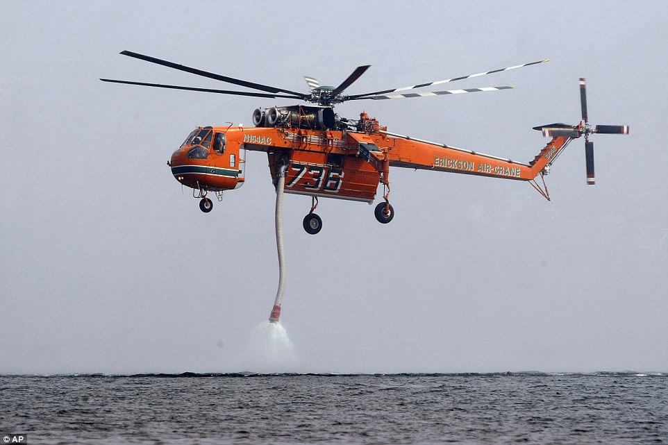 A helicopter comes down to take in water from Lake Chelan, Washington, before flying inland to douse the First Creek wildfire on Sunday